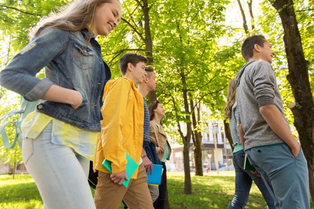 education, high school, learning and people concept - group of happy teenage students walking outdoorsの写真素材