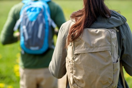 travel, hiking, backpacking, tourism and people concept - close up of couple with backpacks walking...