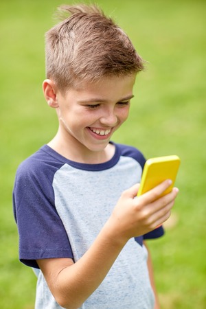 childhood, augmented reality, technology and people concept - happy smiling boy with smartphone...