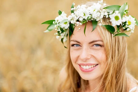 nature, summer holidays, vacation and people concept - face of happy woman in wreath of flowersの写真素材