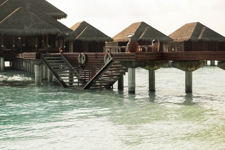 travel, tourism, vacation and summer holidays concept - bungalow huts in sea water on exotic resort beachの写真素材