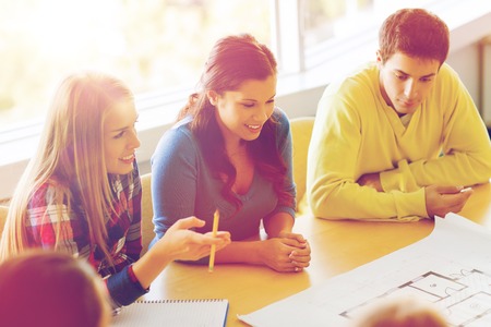 education, school, architecture and people concept - group of smiling students with blueprint...