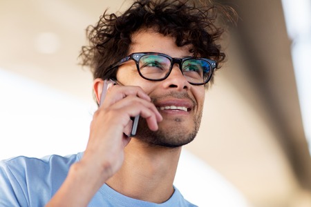 leisure, technology, communication and people concept - man in eyeglasses calling on smartphone on...