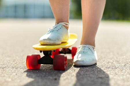 skateboarding, leisure, extreme sport and people concept - close up of teenage girl legs riding...
