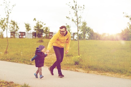 family, childhood, fatherhood, leisure and people concept - happy father and little son walking outdoorsの写真素材