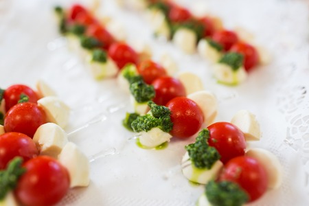 food, catering, cooking and eating concept - close up of mozzarella cheese and cherry tomato canapeの写真素材