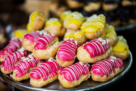 food, junk-food and eating concept - close up of glazed eclair pile on serving tray