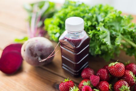healthy eating, food, dieting and vegetarian concept - close up of bottle with beetroot juice, fruits and vegetables on wooden tableの写真素材