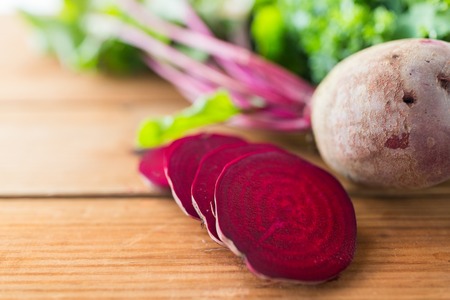 healthy eating, food, dieting and vegetarian concept - close up of sliced beet on wood
