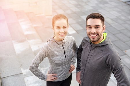 fitness, sport, people and lifestyle concept - smiling couple outdoors on city streetの写真素材
