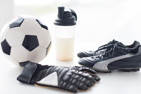 sport, soccer and sports equipment concept - close up of ball, football boots, goalkeeper gloves and protein shake bottle with drinkの写真素材