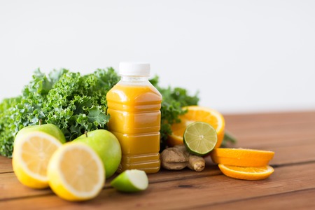healthy eating, food, dieting and vegetarian concept - bottle with orange juice, fruits and vegetables on wooden tableの写真素材