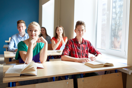 education, learning and people concept - group of students with books at school lessonの写真素材