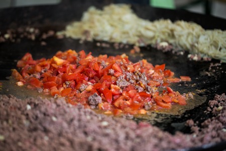 cooking, asian kitchen, sale and food concept - vegetables frying on big wok pan at street marketの写真素材