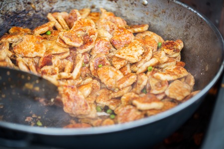 cooking, asian kitchen, sale and food concept - close up of meat frying in wok pan at street marketの写真素材