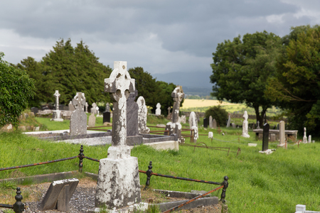 ancient monument and burial concept - old headstones and ruins on celtic cemetery graveyard in irelandの写真素材