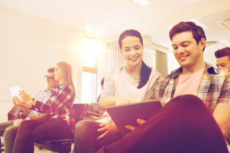 education, high school, teamwork and people concept - group of smiling students with tablet pc computers sitting in lecture hallの写真素材