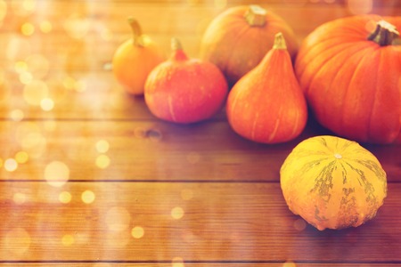 food, harvest, season and autumn concept - close up of pumpkins on wooden table at homeの写真素材