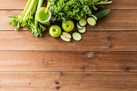 healthy eating, food, dieting and vegetarian concept - close up of bottle with green juice, fruits and vegetables on wooden tableの写真素材
