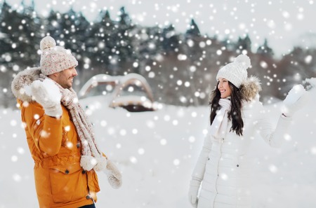 people, season, love and leisure concept - happy couple playing snowballs in winterの写真素材