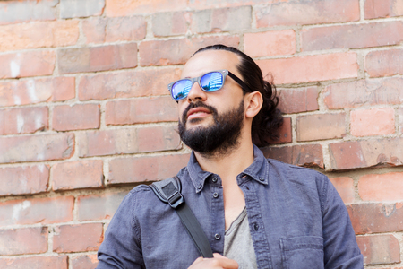 travel, tourism, lifestyle and people concept - happy smiling man with backpack standing at city street wallの写真素材
