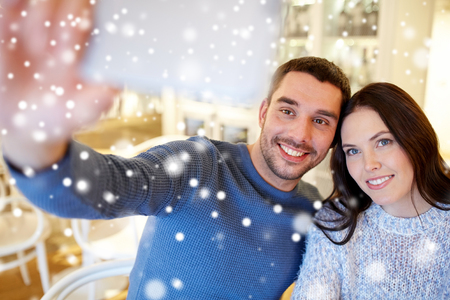people, technology and dating concept - happy couple taking smartphone selfie at cafe or restaurantの写真素材