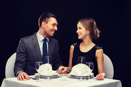 restaurant, couple and holiday concept - smiling couple looking at each other at restaurantの写真素材