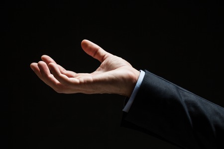 business, people and advertisement concept - close up of businessman with empty hand over black