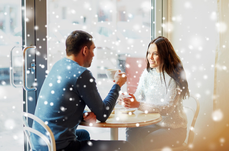 people, communication and dating concept - happy couple drinking tea and coffee at cafeの写真素材