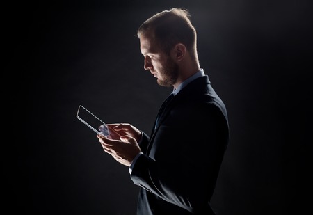 business, people and future technology concept - close up of businessman with transparent tablet pc computer over blackの写真素材
