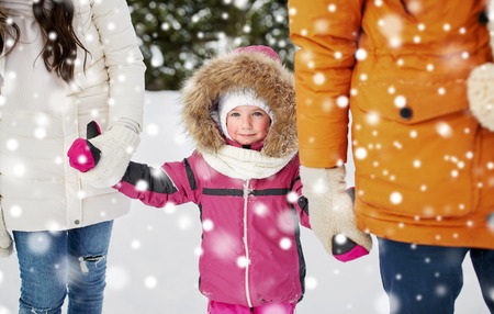 parenthood, fashion, season and people concept - happy family with child in winter clothes outdoorsの写真素材