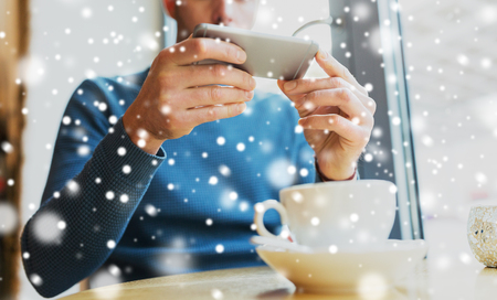 people, communication and technology concept - close up of man with smartphones at cafeの写真素材