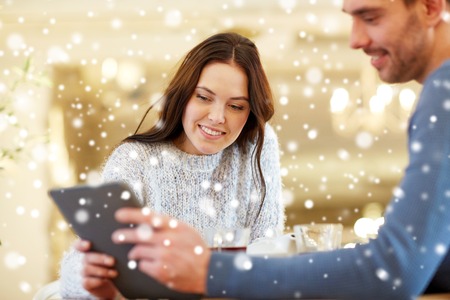 people, communication and dating concept - happy couple with tablet pc computer at cafe or restaurantの写真素材