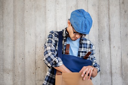 people, style, leisure and lifestyle - young hipster man looking for something in his bag