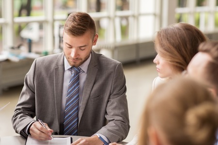 business, cooperation, people and partnership concept - business team with papers or contract...