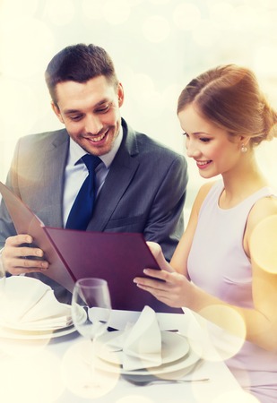 restaurant, couple and holiday concept - smiling couple with menu at restaurantの写真素材