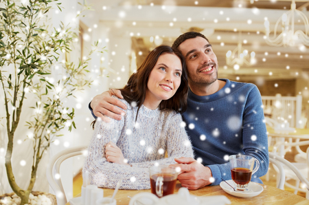 people, communication and dating concept - happy couple drinking tea and hugging at cafe or restaurantの写真素材