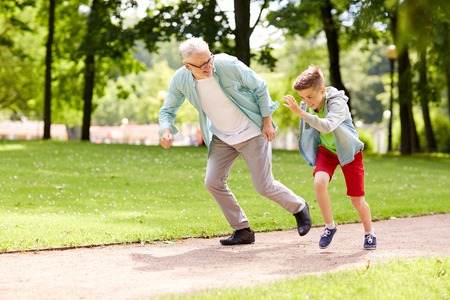 family, generation and people concept - happy grandfather and grandson racing at summer parkの写真素材