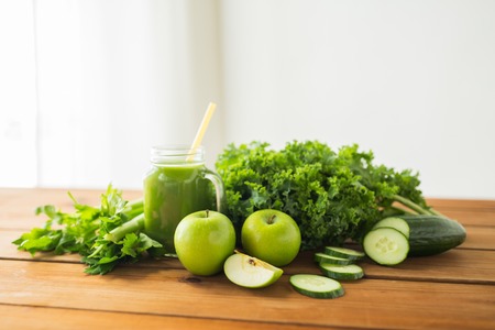 healthy eating, food, dieting and vegetarian concept - close up of glass jug with green juice, fruits and vegetables on wooden tableの写真素材