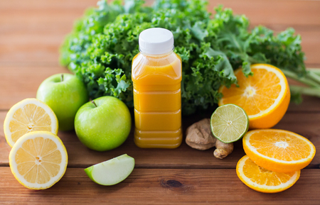 healthy eating, food, dieting and vegetarian concept - bottle with orange juice, fruits and vegetables on wooden tableの写真素材