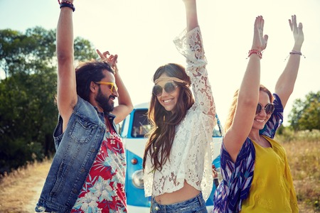 nature, summer, youth culture and people concept - happy young hippie friends dancing over minivan car outdoorsの写真素材