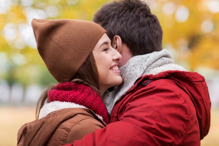 love, relationships, season and people concept - happy young couple hugging in autumn parkの写真素材