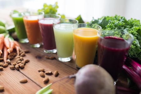 healthy eating, drinks, diet and detox concept - glasses with different fruit or vegetable juices and food on table