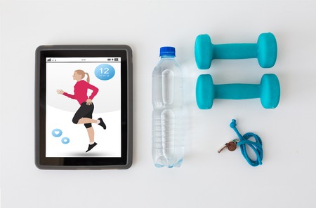 sport, healthy lifestyle, fitness and  technology concept - tablet pc computer with dumbbells, whistle and water bottle over white backgroundの写真素材
