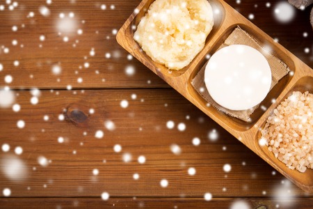beauty, spa, bodycare, natural cosmetics and wellness concept - soap with himalayan pink salt and scrub in wooden bowl on table over snowの写真素材