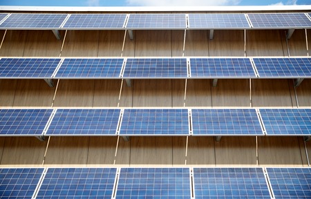 energy sources, power, environment and ecology concept - solar battery panels on building facadeの写真素材