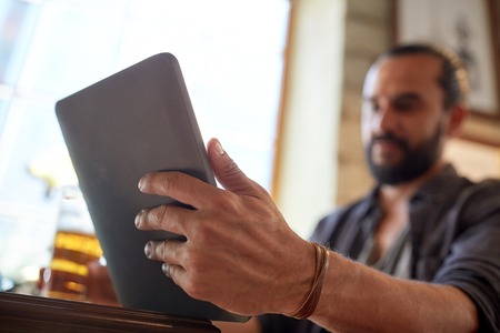 people, leisure and technology concept - close up of man with tablet pc computer drinking beer at...