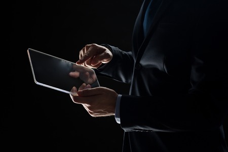 business, people and future technology concept - close up of businessman hands with transparent tablet pc computer over blackの写真素材