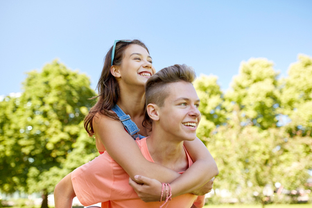 holidays, vacation, love and people concept - happy smiling teenage couple having fun at summer parkの写真素材
