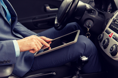 transport, business trip, technology and people concept -close up of young man with tablet pc computer driving carの写真素材